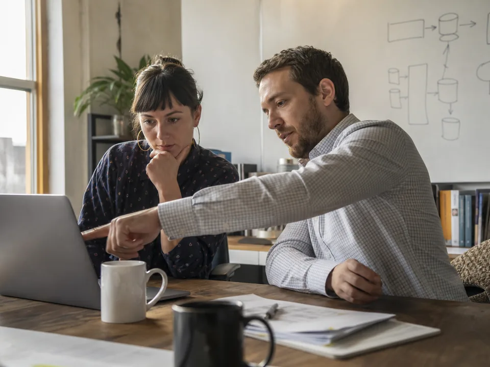 Two agency colleagues planning a marketing data pipeline budget at a whiteboard